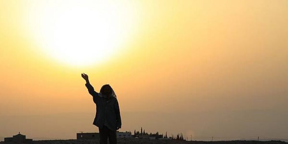 photo of person lifting their arm towards the rising or setting sun