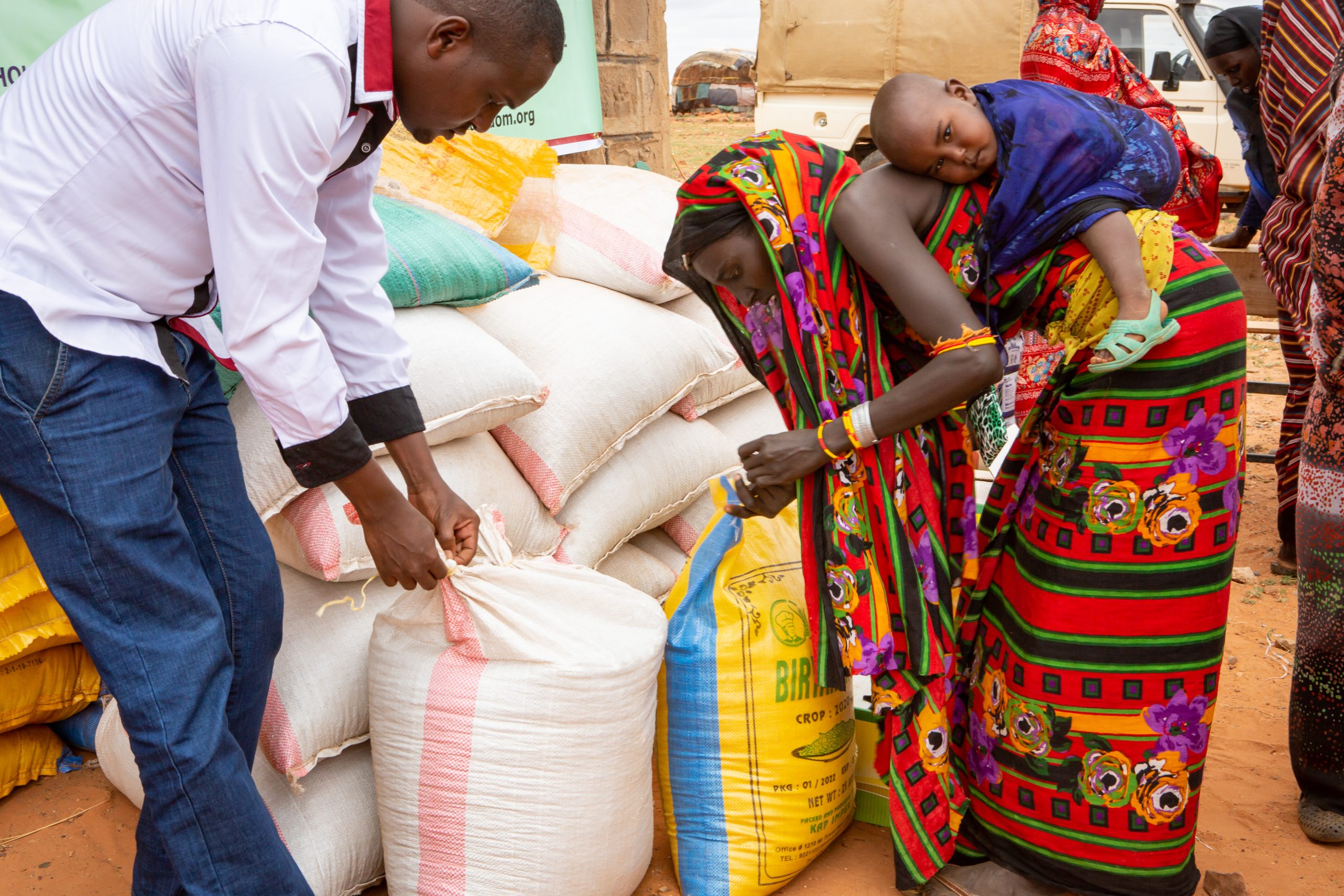 Food-distribution.-Wakera-Ibrae-Caritas-Marsabit Man giving a sack of food to a woman with a child on her back